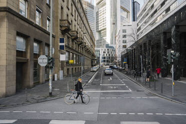 Woman with bicycle crossing street in the city, Frankfurt, Germany - AHSF02213