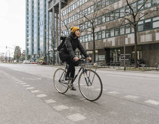 Woman riding bicycle in the city, Frankfurt, Germany - AHSF02219