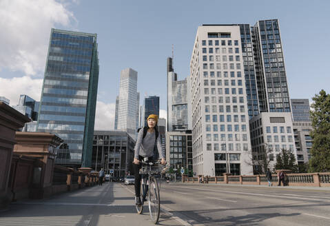 Woman riding bicycle in the city, Frankfurt, Germany - AHSF02225