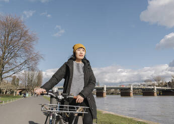 Frau mit Fahrrad am Flussufer, Frankfurt, Deutschland - AHSF02228