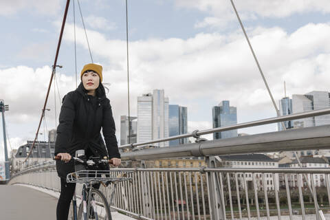 Frau fährt Fahrrad auf einer Brücke, Frankfurt, Deutschland, lizenzfreies Stockfoto