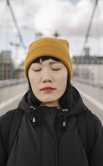 Porträt einer Frau mit geschlossenen Augen auf einer Brücke - AHSF02234