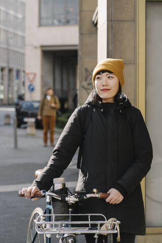 Portrait of confident woman with bicycle in the city, Frankfurt, Germany stock photo
