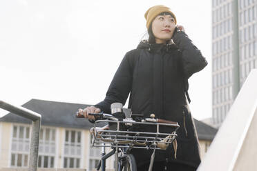 Woman with bicycle on the phone in the city, Frankfurt, Germany - AHSF02242