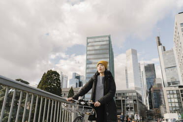 Woman with bicycle in the city, Frankfurt, Germany - AHSF02249