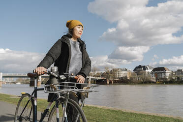 Frau mit Fahrrad am Flussufer, Frankfurt, Deutschland - AHSF02250