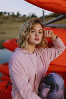 Portrait of young blond woman wearing pink hoodie sweater on jetty - AGGF00010