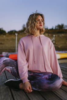 Portrait of young blond woman wearing pink hoodie sweater on jetty - AGGF00012