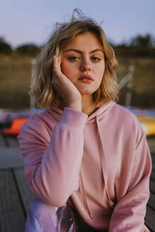 Portrait of young blond woman wearing pink hoodie sweater on jetty - AGGF00013