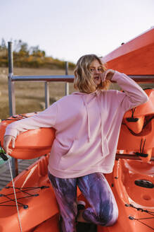 Portrait of young blond woman wearing pink hoodie sweater on jetty - AGGF00014