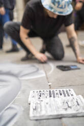 Straßenkunst, Straßenkünstler, der auf den Bürgersteig zeichnet und sein Smartphone benutzt - FBAF01469