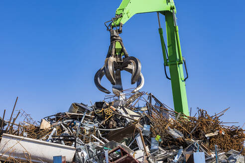 Germany, Baden-Wurttemberg, Stuttgart, Mechanical claw over heap of scrap metal lying in junkyard - WDF05947