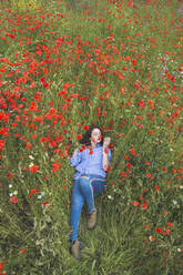 Young woman lying in poppy field - FVSF00107