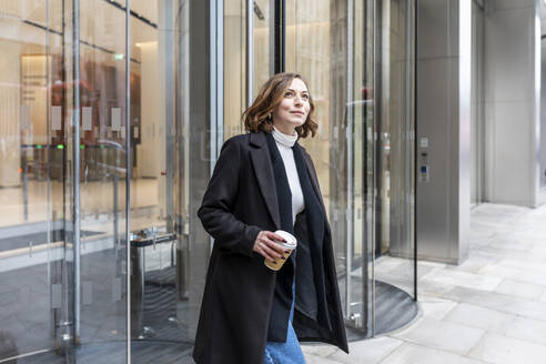 Woman in the city coming out from revolving door, London, UK - WPEF02764