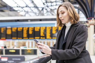 Woman at train station using mobile phone, London, UK - WPEF02776