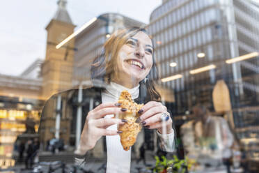 Glückliche Geschäftsfrau bei einem Snack in einem Café in der Stadt - WPEF02782