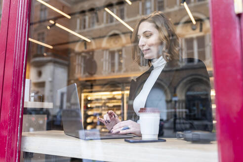 Businesswoman using laptop at a cafe in the city - WPEF02784