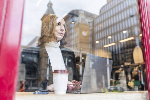 Geschäftsfrau mit Laptop in einem Café in der Stadt, lizenzfreies Stockfoto