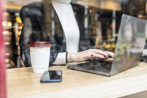 Close-up of businesswoman using laptop at a cafe in the city - WPEF02787