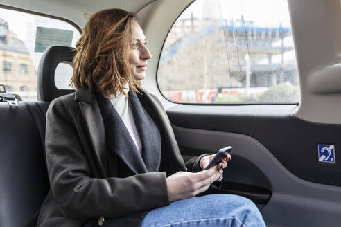 Businesswoman in the rear of a taxi looking out of the window, London, UK - WPEF02791