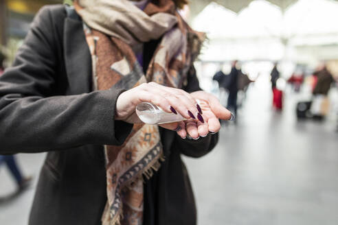 Woman using sanitising hand gel at train station - WPEF02797
