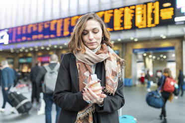 Frau benutzt desinfizierendes Handgel am Bahnhof - WPEF02798