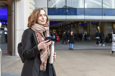 Porträt einer Frau mit Mobiltelefon vor einem Bahnhof, London, UK - WPEF02801