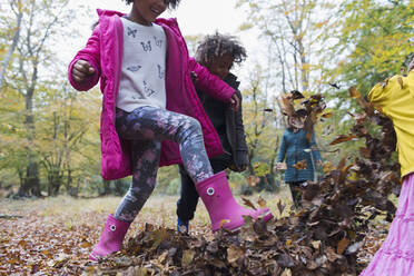 Verspielte Kinder kicken im Herbstlaub - CAIF26289