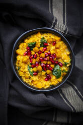 Bowl of vegan curry with red lentils, sweet potatoes, spinach, roasted turmeric chick-peas, pomegranate seeds and cilantro - LVF08786