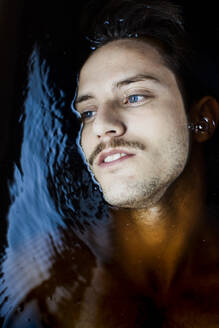 Portrait of pensive young man with blue eyes in water - GMLF00008