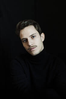 Portrait of young man against black background - GMLF00014