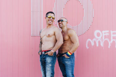 Porträt eines schwulen Paares ohne Hemd vor einer rosa Wand - JCMF00575