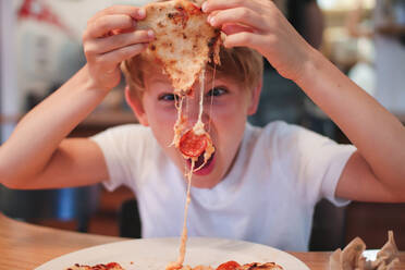 Porträt eines Jungen, der eine Peperoni-Pizza isst - EYF03798