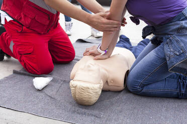 Midsection Of Instructor Teaching Paramedic While Performing Cpr On Dummy - EYF03862