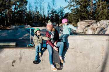 Mom and her kids playing and having fun at a skatepark outside - CAVF79062