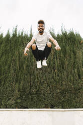 Porträt eines glücklichen jungen Mannes, der im Freien in die Luft springt - XLGF00023