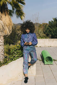 Stylish young woman wearing tracksuit and using cell phone outdoors - AGGF00021