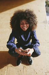 Stylish young woman wearing tracksuit and using cell phone outdoors - AGGF00033