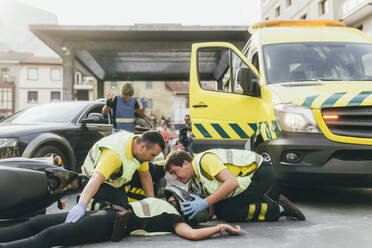 Sanitäter helfen Unfallopfer nach Motorrollerunfall - MTBF00378