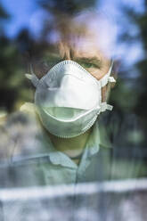 Mature man with protective mask looking through of the window, looking at camera - MCVF00291