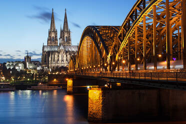 Beleuchtete Hohenzollernbrücke über den Rhein am Kölner Dom in der Abenddämmerung - EYF03978