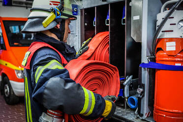 Feuerwehrmann ordnet Schlauch in Rack auf der Feuerwache - EYF03988
