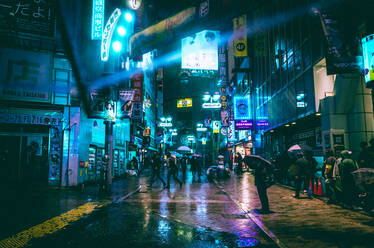 Menschen auf beleuchteter Straße bei Nacht während der Regenzeit - EYF03997