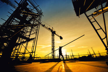 Silhouette Man Working At Construction Site Against Sky During Sunset - EYF04002