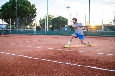 Volle Länge des jungen Mannes, der Tennis auf dem Feld spielt - EYF04070