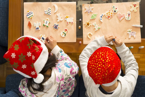 High Angle View of Children Wearing Santa Hut Herstellung Handwerk am Tisch, lizenzfreies Stockfoto