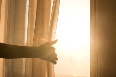 Abgeschnittene Hand hält Vorhang am Fenster - EYF04155