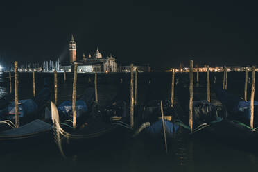 Italien, Venedig, Reihe von vertäuten Gondeln bei Nacht - FMOF00961