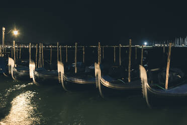 Italien, Venedig, Reihe von vertäuten Gondeln bei Nacht - FMOF00962