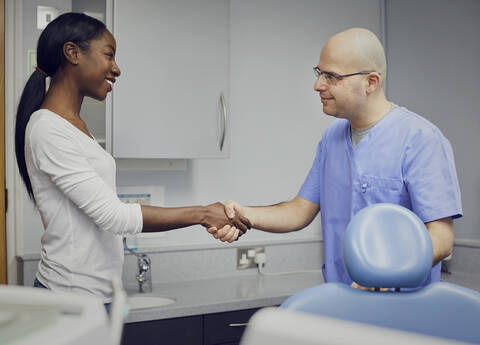 Dentist shaking hands with patient stock photo